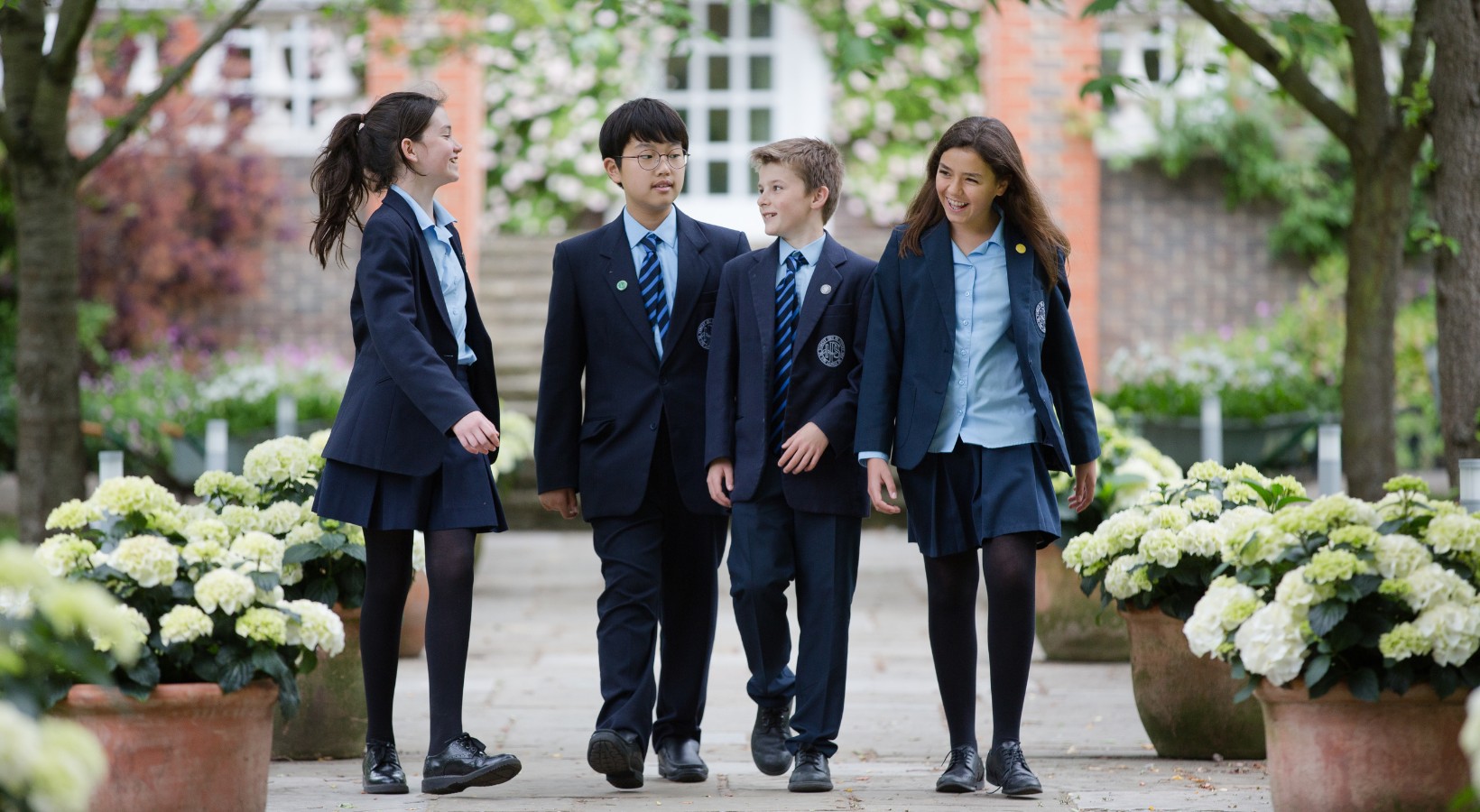 Senior pupils are smiling while walking through the beautiful campus of Ibstock Place School