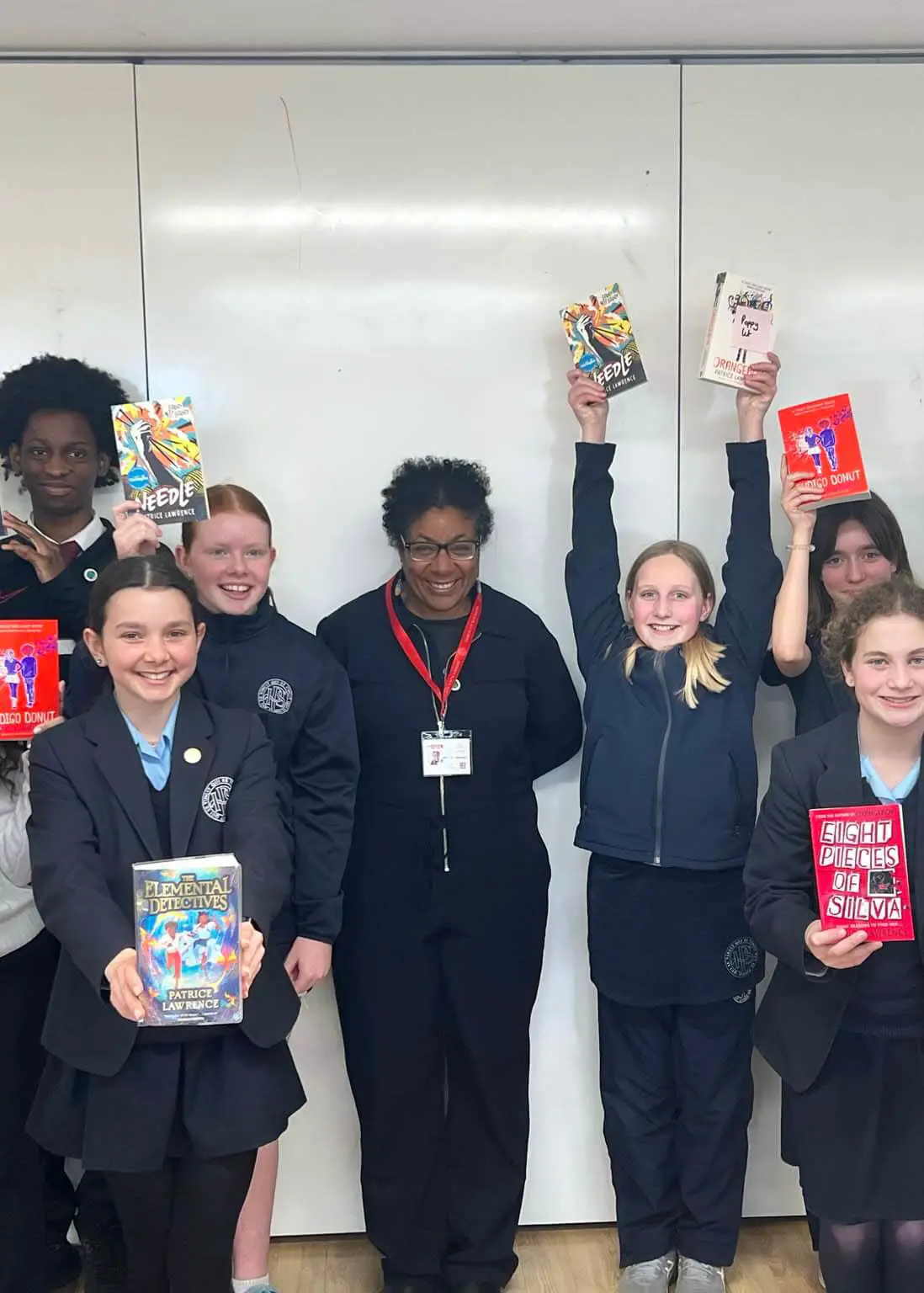 Pupils standing with Patrice Lawrence with his books in their hands.