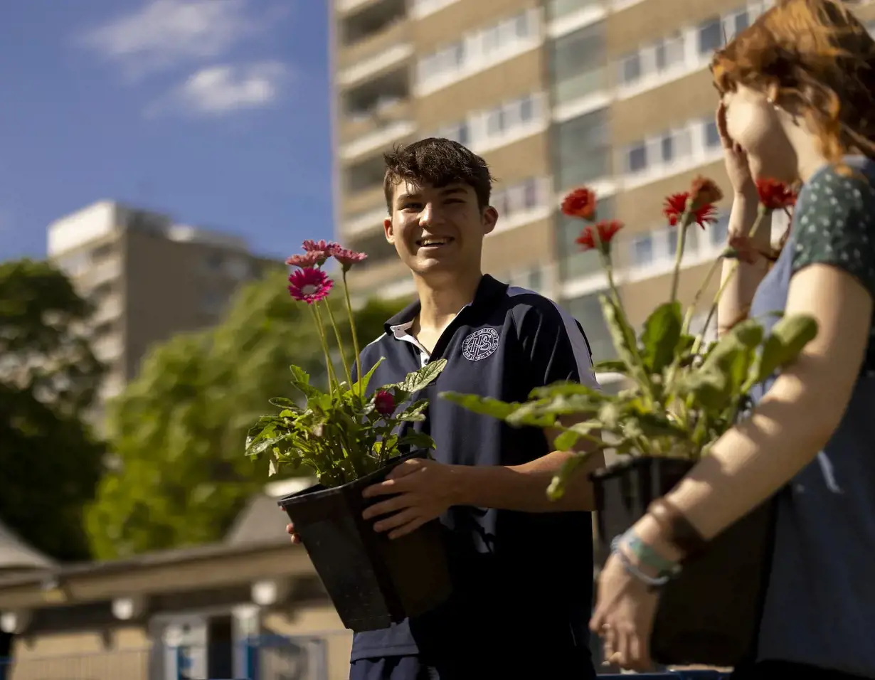 Senior pupils holding pots of flowers at Ibstock Place School, near Richmond.