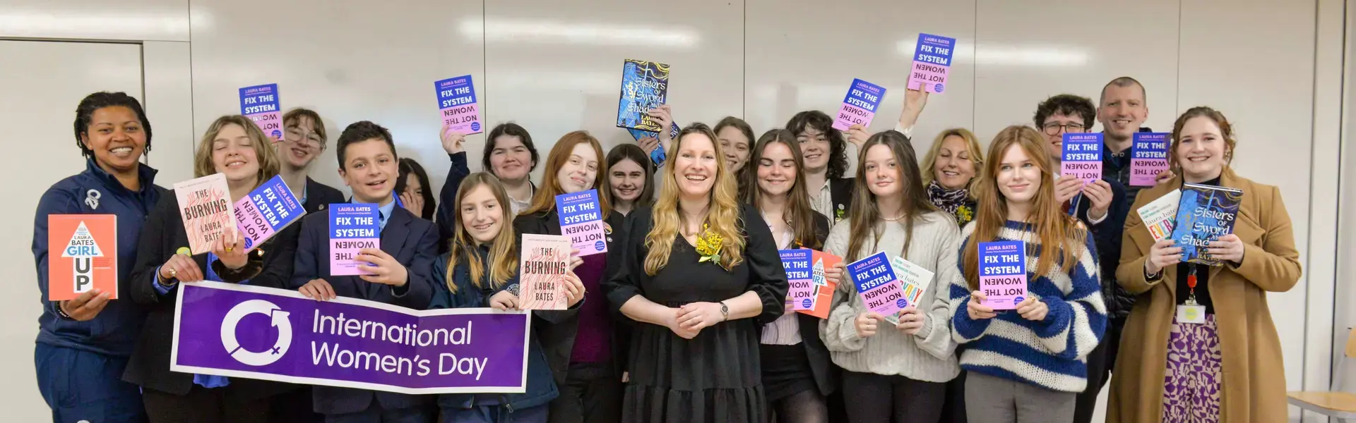 Laura Bates and Senior pupils standing with her book in their hands at Ibstock Place School, Roehampton, a private school near Richmond, Barnes, Putney, Kingston, & Wandsworth
