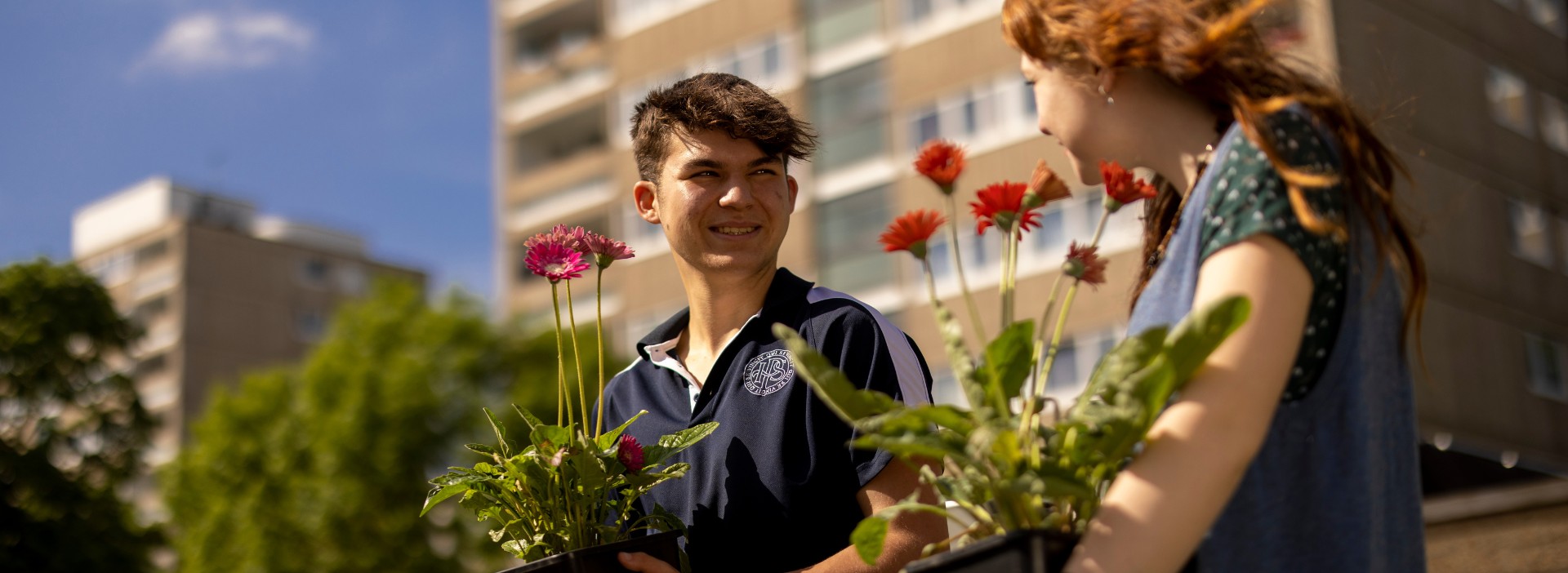 Senior pupils holding pots of flowers at Ibstock Place School.