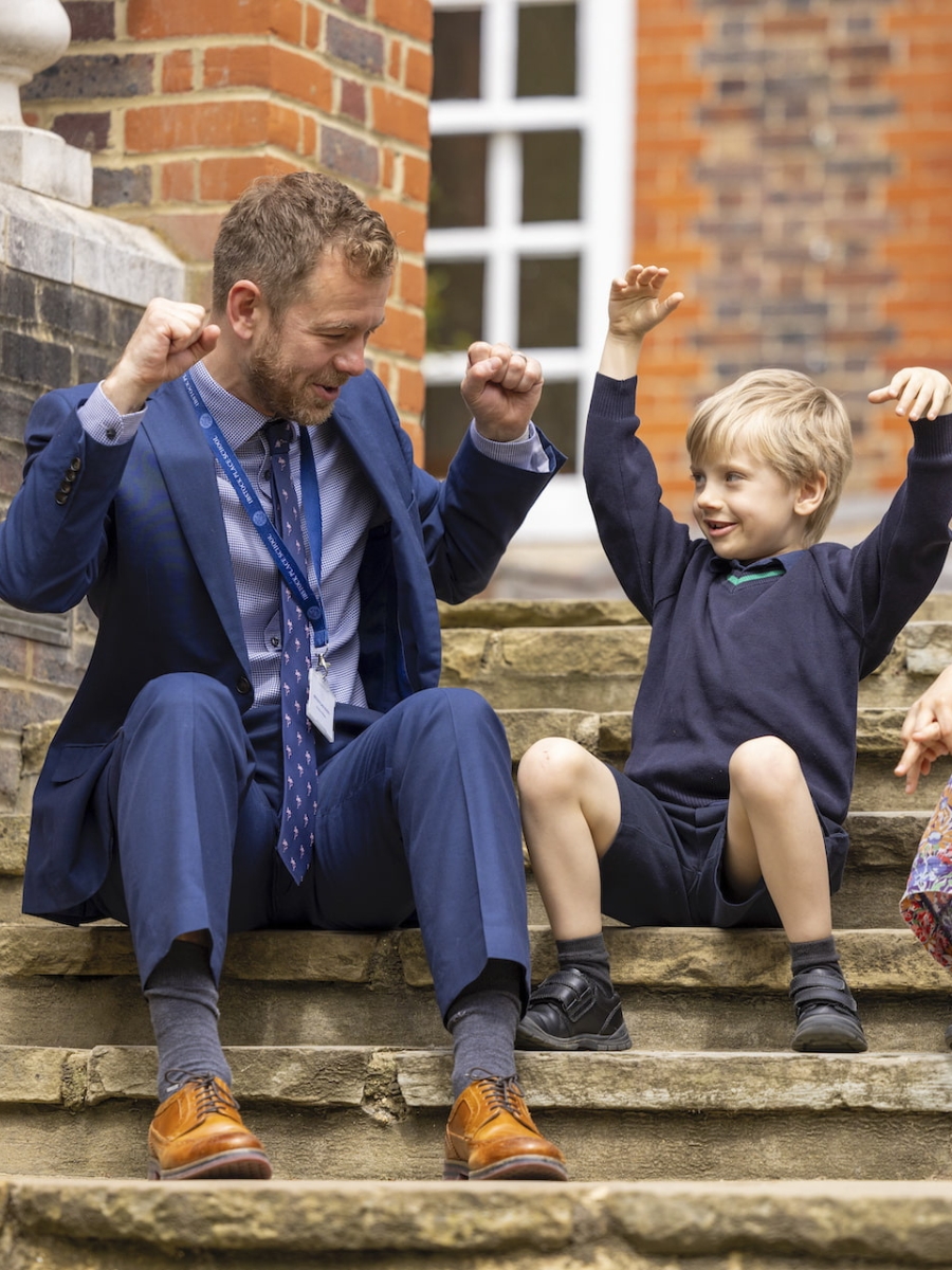 Pre-prep pupil sitting on the stairs with their teacher.