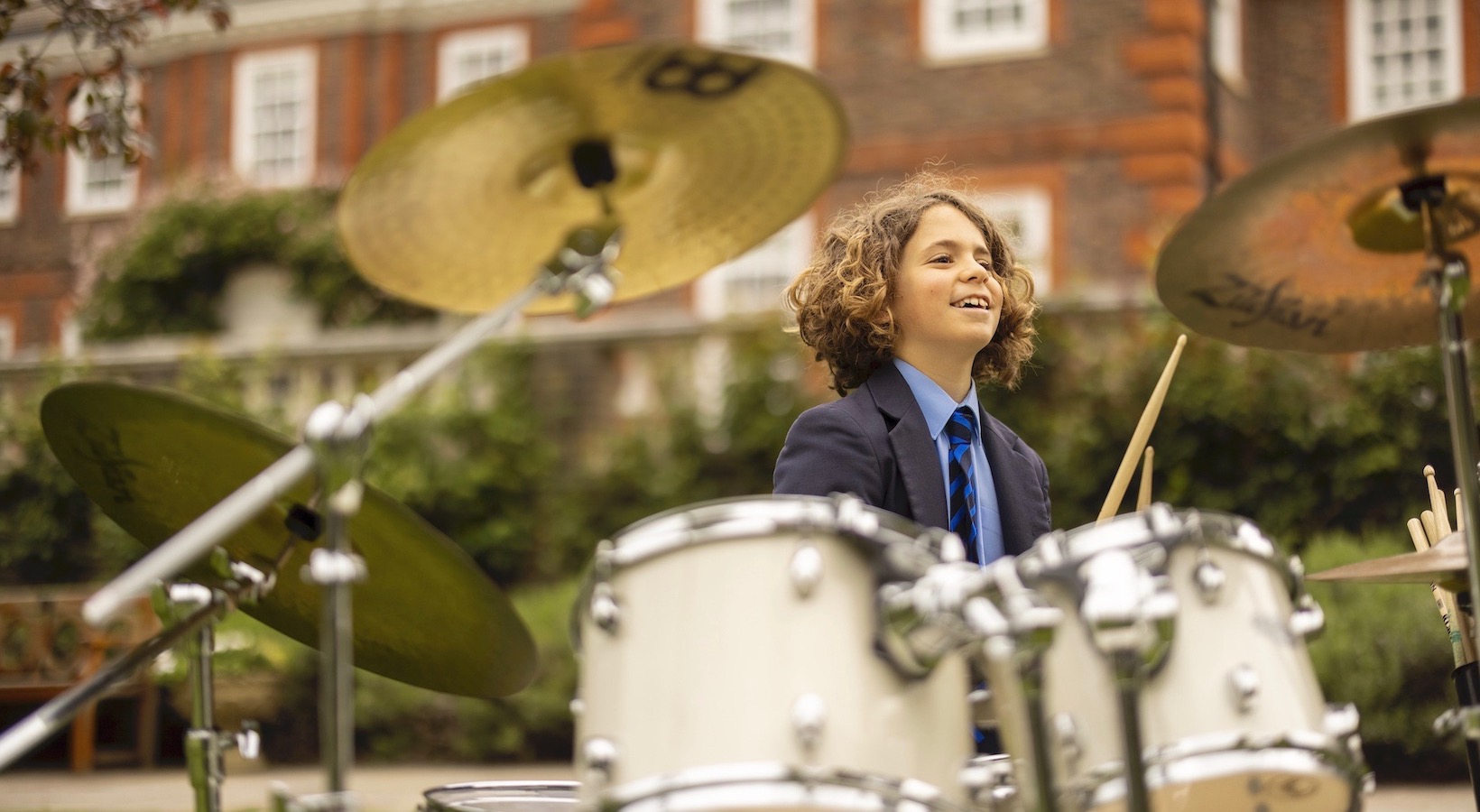 Senior pupil playing the drum at Ibstock Place School, a private school near Richmond