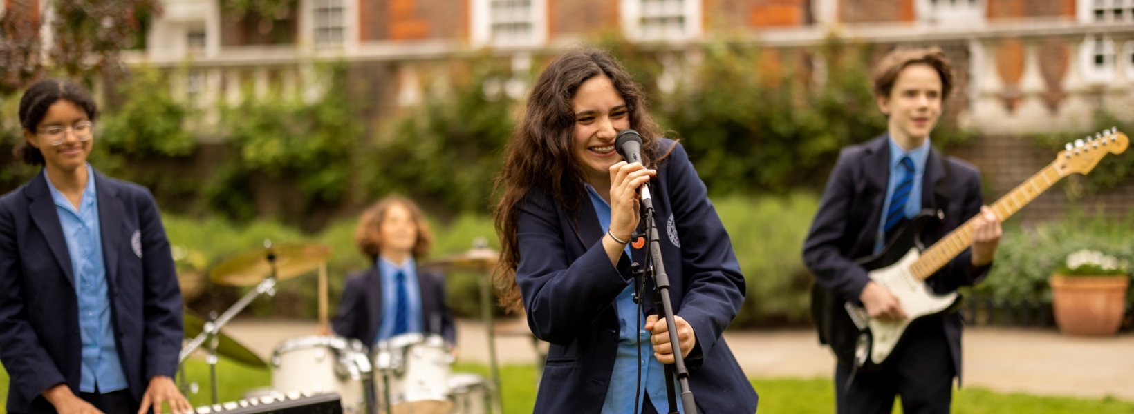Senior pupils in a band playing their instruments and singing in the campus of Ibstock Place School