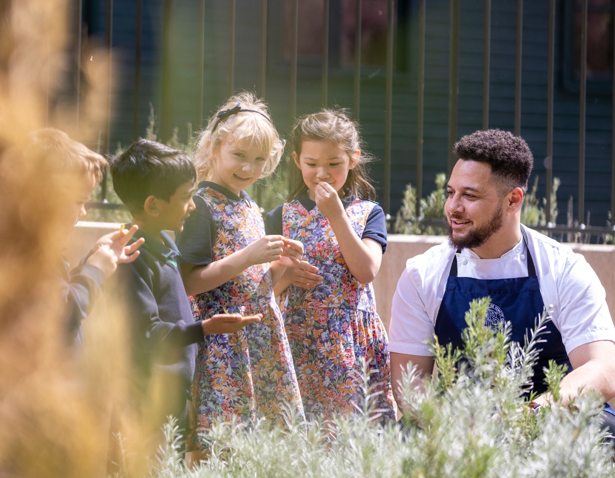 Catering manager teaching pre-prep pupils about different plants on campus.