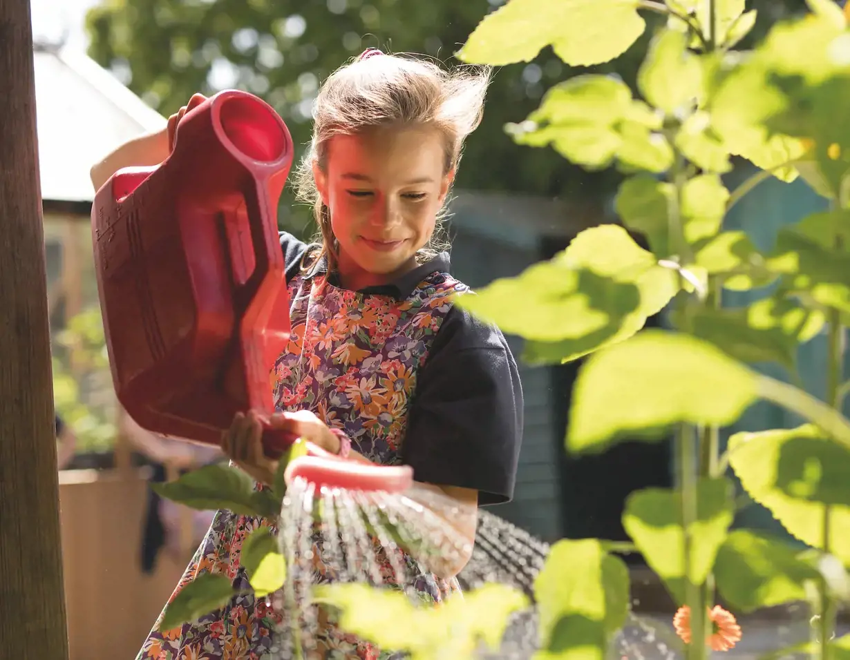 Prep pupil watering plants of Ibstock Place School, a private school near Richmond, Barnes, Putney, Kingston, & Wandsworth