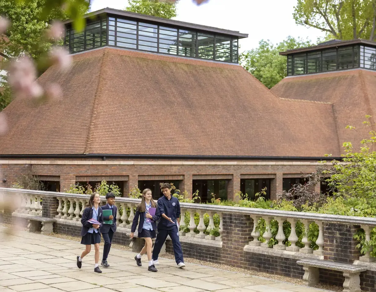 Senior pupils walking around the campus with books at Ibstock Place School, co-educational a private school near Richmond, Barnes, Putney